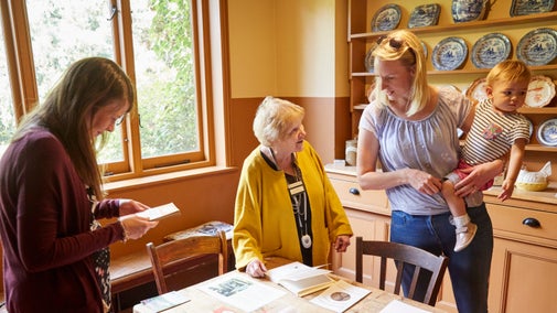 A volunteer speaks with visitors in the kitchen at Shaw's Corner, Hertfordshire